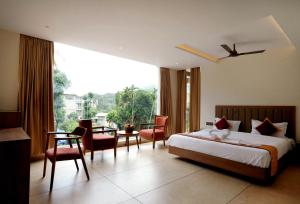a bedroom with a bed and chairs and a large window at Bluemist Resorts in Athirappilly