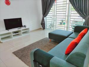 een woonkamer met een blauwe bank en een televisie bij OOI Homestay Alor Setar in Alor Setar