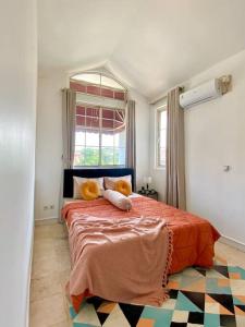 una camera da letto con un letto con lenzuola arancioni e una finestra di DnS House a Babakan Madang