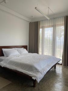 ein großes Bett in einem Schlafzimmer mit einem großen Fenster in der Unterkunft Amidst wind in Wang Nam Khieo