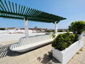 a white bench sitting under a large umbrella at - Casa Abades dos dormitorios - in Abades