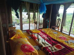 a bedroom with two beds with yellow and red sheets at Banlung Hill Top House &Trekking in Phumĭ Pôy