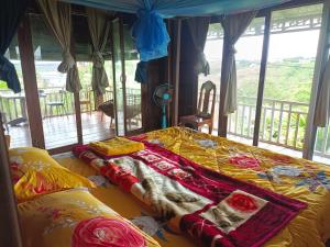 a bedroom with a bed with a blanket on it at Banlung Hill Top House &Trekking in Phumĭ Pôy