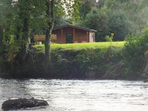 a cabin on a hill next to a river at KILLARNEYCABINSie Stunning & Spacious Scandanavian Timber Lodges in Killarney