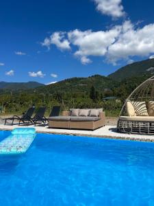 a swimming pool with chairs and a couch at Garemo in Ambrolauri
