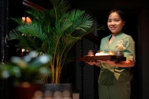 a woman holding a tray with a cake on it at Le Chanvre Hanoi Hotel & Spa in Hanoi +97 photos