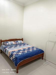 Schlafzimmer mit einem Bett mit einer blauen und weißen Bettdecke in der Unterkunft Homestay Yasmeen in Marang