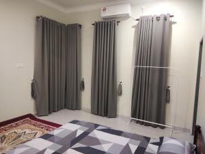 ein Schlafzimmer mit grauen Vorhängen und einem Bett in einem Zimmer in der Unterkunft Homestay Yasmeen in Marang