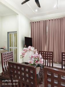 ein Esszimmer mit einem Tisch mit rosa Blumen drauf in der Unterkunft Homestay Yasmeen in Marang