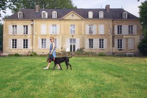 a woman walking a dog in front of a large house at Appartement du Commun au Château de Chanteloup in La Croix