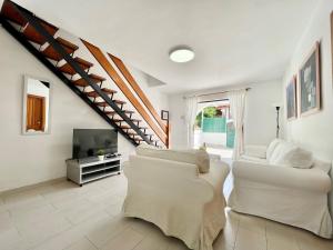 una sala de estar con muebles blancos y una escalera. en Sunlight Place Bungalow, en San Bartolomé