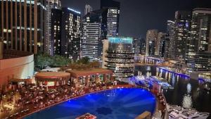 Luxury Address Res DubaiMarina Studio1 Frank&Frank في دبي: اطلالة على مدينة بالليل مع مسبح