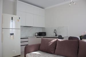 a kitchen with a couch and a white refrigerator at Новая квартира в ЖК "Millennium Park" in Promyshlennyy