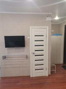 a room with a tv on a wall with a door at Однокомнатная квартира-студия в Гагре! Море солнца in Gagra