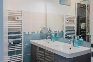 La salle de bains est pourvue d'un lavabo blanc et d'un miroir. dans l'établissement Gîte de la Marina dans la presqu'île de Lézardrieux, à Lézardrieux