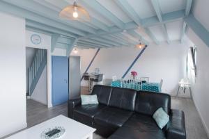 Gîte de la Marina dans la presqu'île de Lézardrieux في Lézardrieux: غرفة معيشة مع أريكة جلدية سوداء وطاولة