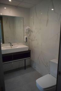 ein Badezimmer mit einem Waschbecken, einem WC und einem Spiegel in der Unterkunft HOTEL VICTORIA in Arinsal