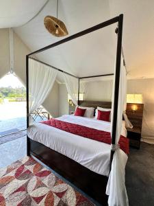 a bedroom with a canopy bed with red pillows at Redberry's Luxury Stay in Somvārpet