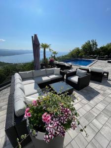 een patio met een bank, bloemen en een zwembad bij Villa White Pearl Diamond Haus B, Opatija mit Meerblick & Pool in Opatija