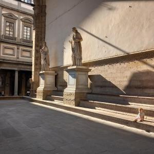 ein Kind auf dem Boden vor zwei Statuen in der Unterkunft Appartamento centro storico Firenze, Luna House in Florenz