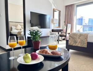 a table with a plate of food and two glasses of orange juice at Luxury Address Res DubaiMarina Studio1 Frank&Frank in Dubai