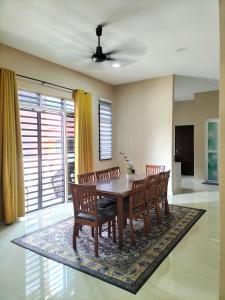 a dining room with a table and chairs on a rug at ADSA homestay in Kampong Wakaf Tengah