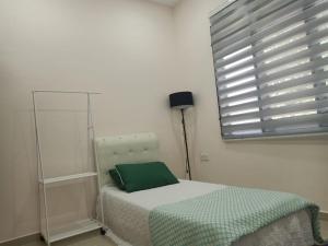 ADSA homestay في Kampong Wakaf Tengah: غرفة نوم بسرير ومخدة خضراء ونافذة