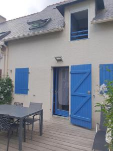 een huis met blauwe deuren en een tafel op een terras bij Maison à Quiberon in Quiberon