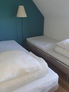 Maison à Quiberon في كويبيرون: سريرين بيض في غرفة بها مصباح
