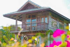a wooden house with a balcony on top of it at baanchandra in Chiang Mai