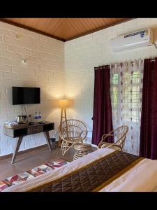 a bedroom with a bed and a desk and a television at Redberry's Luxury Stay in Somvārpet