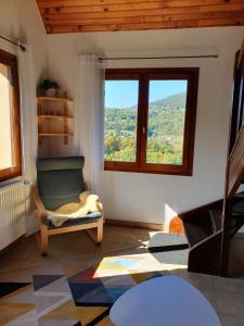 sala de estar con ventana grande y silla en Le Chant du Loriot en Labaroche