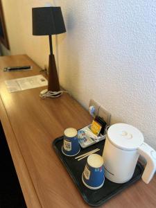 uma bandeja com uma chávena de café e três chávenas numa secretária em Kyriad Marne-La-Vallée Torcy em Torcy