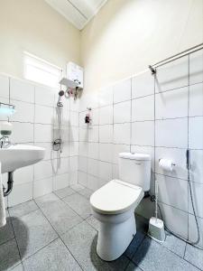 La salle de bains blanche est pourvue de toilettes et d'un lavabo. dans l'établissement Juni Residence, à Pineleng