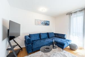 a living room with a blue couch and a tv at Lit Living: Luxus - Box Spring - Parking - Terrace in Ludwigshafen am Rhein