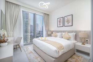 een witte slaapkamer met een groot bed en een groot raam bij Vogue Downtown - Forte Opera District by Emaar in Dubai