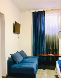 ein Wohnzimmer mit einem blauen Sofa und einem Tisch in der Unterkunft Hotel Sunny in Achalziche
