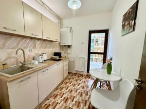 eine Küche mit weißen Schränken, einem Tisch und einem Waschbecken in der Unterkunft Apartament Novara 1 in Craiova