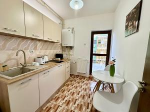 a kitchen with white cabinets and a table and a sink at Apartament Novara 17 in Craiova
