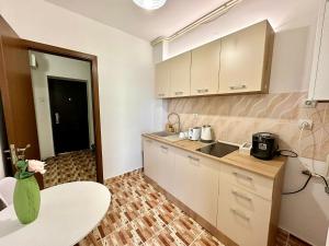a kitchen with white cabinets and a table and a sink at Apartament Novara 17 in Craiova +2 photos