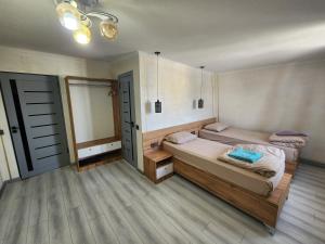 two beds in a room with two doors and wooden floors at Green House Hostel in Dushanbe