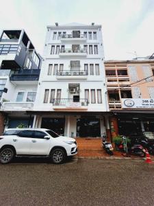 una macchina bianca parcheggiata di fronte a un edificio di Sinakhone Vientiane Hotel a Vientiane