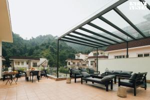 a patio with black chairs and tables and a large glass roof at StayVista at Villa Vaari with Pvt Pool & Gazebo in Dehradun