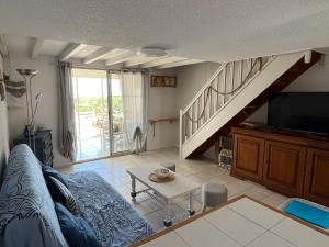 a living room with a couch and a tv and stairs at Panorama Mer in Saint Pierre La Mer