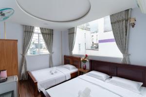 2 Betten in einem Zimmer mit 2 Fenstern in der Unterkunft Sunny Guesthouse2 in Ho-Chi-Minh-Stadt