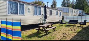 a picnic table and chairs in front of a trailer at Kathy's Warden springs caravan in Leysdown-on-Sea