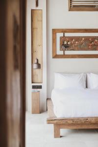 Schlafzimmer mit einem weißen Bett und einem Spiegel in der Unterkunft Kalyana Villa Gili Air in Gili Air