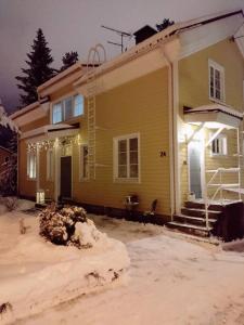 una casa amarilla con nieve delante en Paritalohuoneisto keskustassa, en Valkeakoski