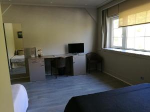 a bedroom with a desk with a computer and a window at Hotel Igeretxe in Getxo