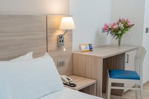 a bedroom with a bed and a desk with a phone at Hotel Portoconte in Porto Conte